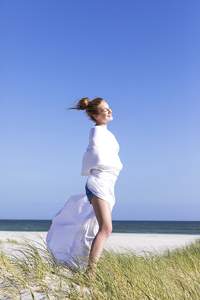 Teenage girl wrapped in white, Grotto Beach, Hermanus, Western Cape, South Africa.