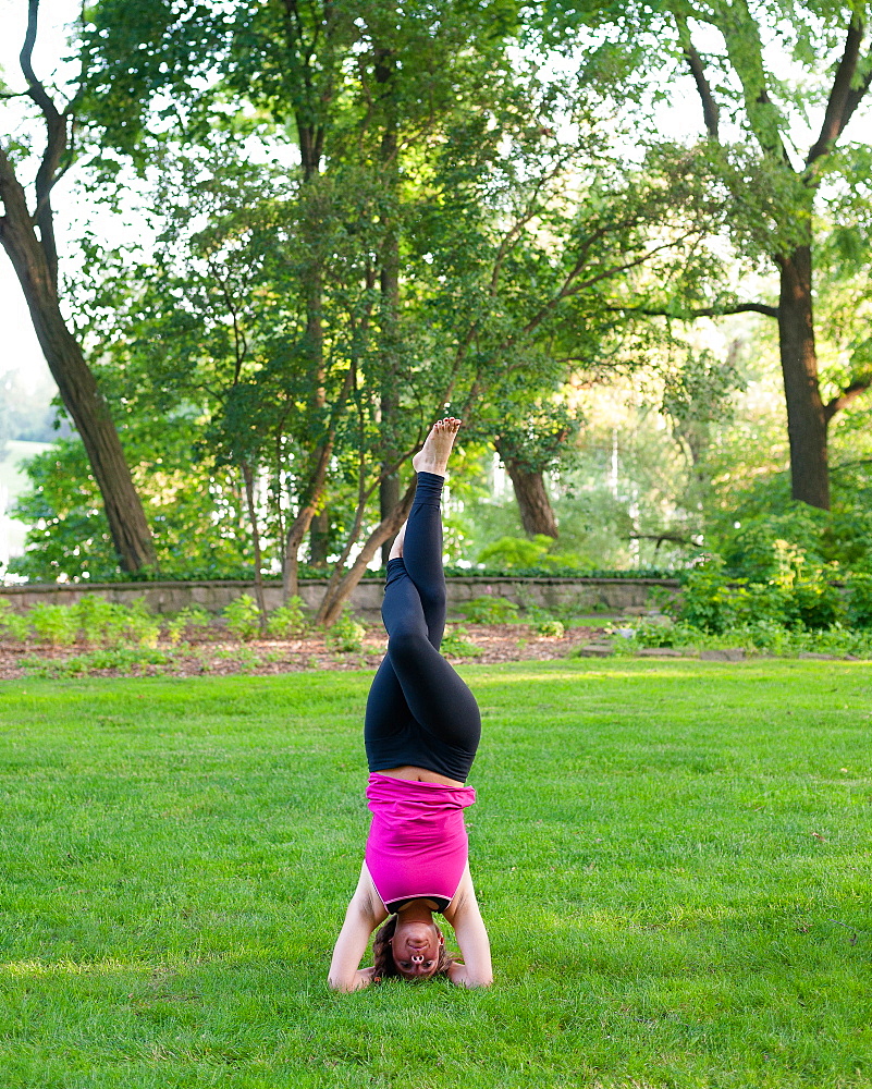 Woman balancing in yoga pose in park.