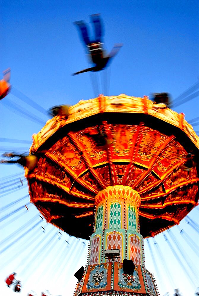 People riding on a chair swing ride or swing carousel seen from below.