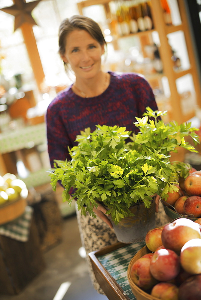 Organic Farmer at Work. A woman working ona farm stand, witha display of fresh produce. Green plants and bowls of apples, Accord, New York, USA