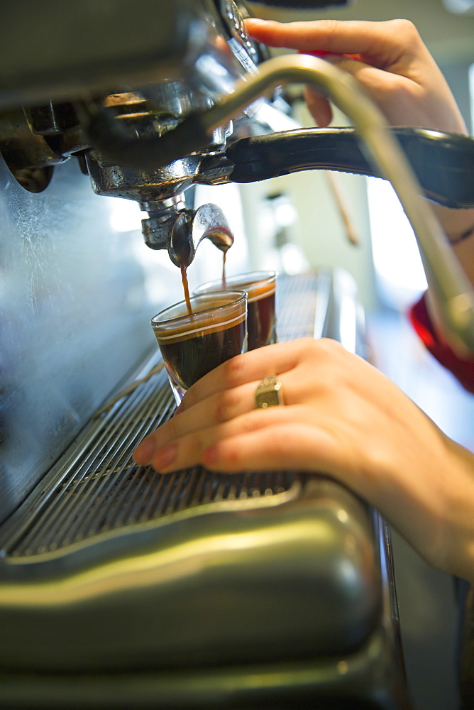 A young woman making coffee using a large coffee machine, Stone Ridge, New York, USA