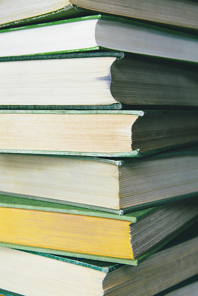 A stack of old hard cover books, with worn edges and paper that is stained or yellowed with age and use. 