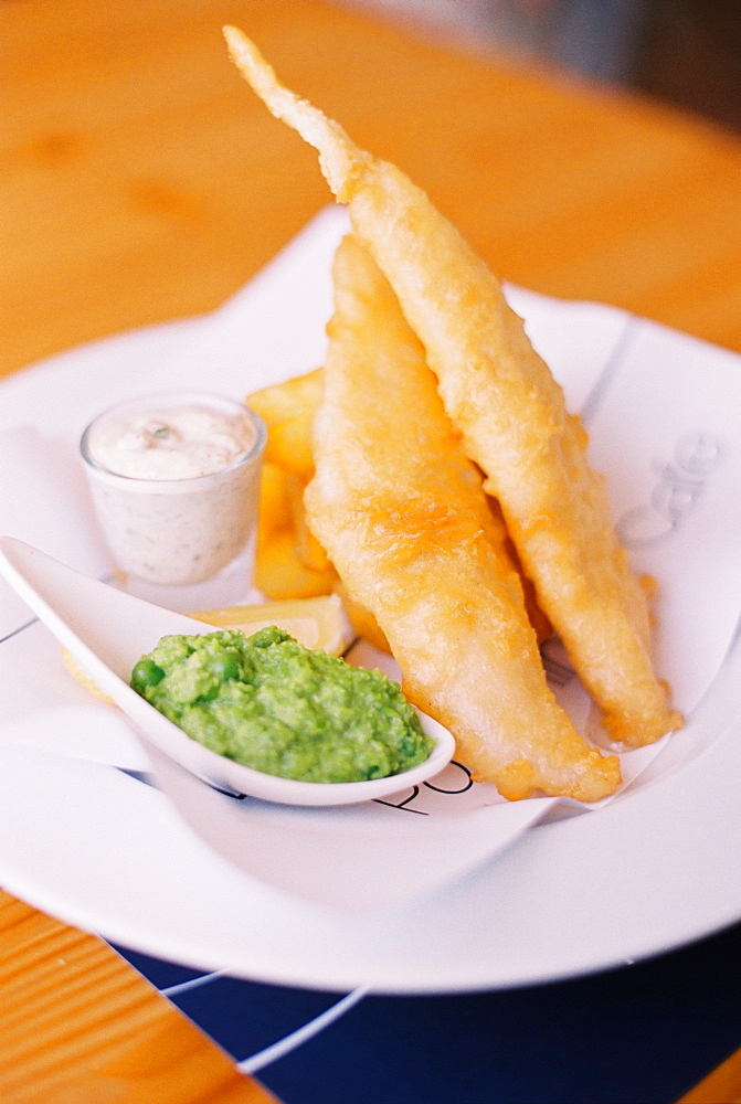 Traditional food, fried battered fish and chips, with mushy peas and tartare sauce on a plate, England