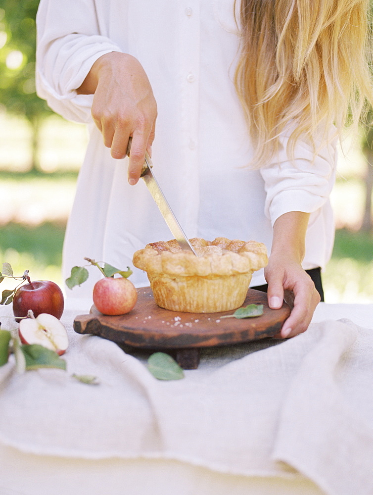 An apple orchard in Utah. Woman standing at a table with food, cutting an apple pie, Sataquin, Utah, United States of America