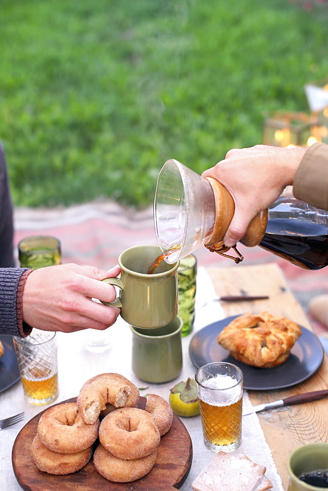 An apple orchard in Utah. Two people sitting at a table with food and drink, pouring coffee, Sataquin, Utah, United States of America