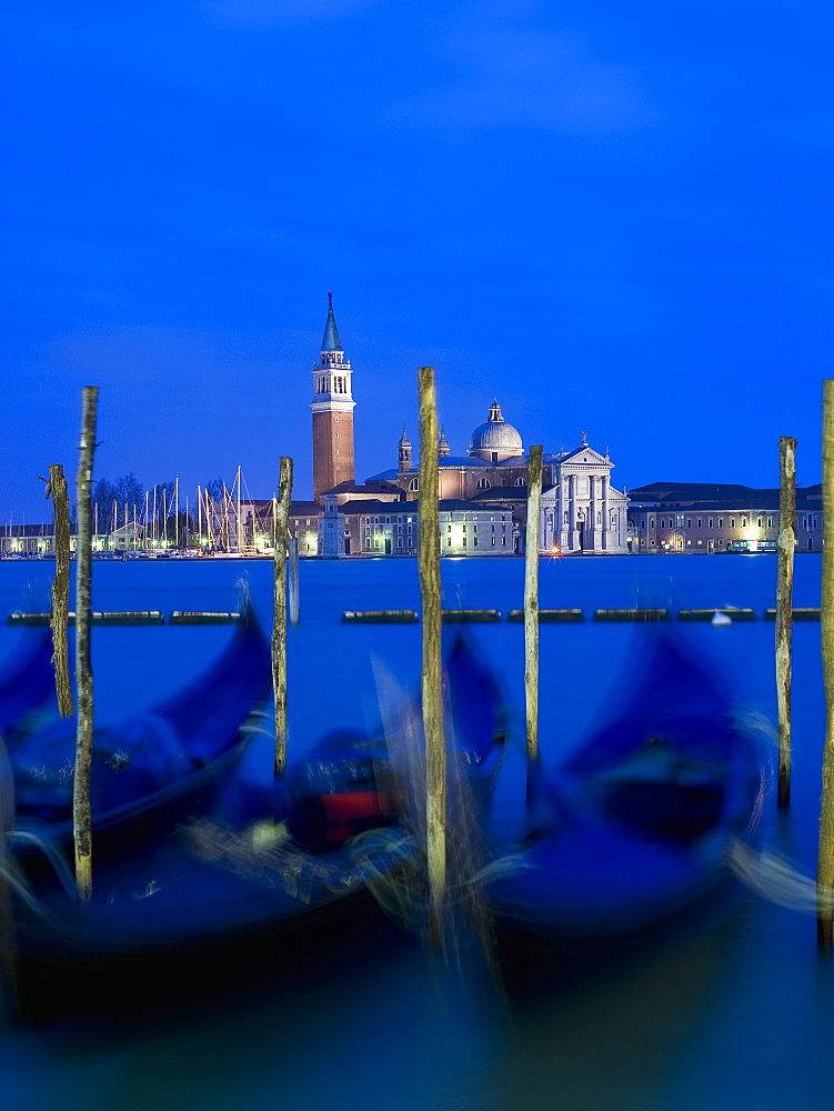 A view from the Riva degli Schiavoni and the Piazza San Marco across the water to the island and church of San Giorgio Maggiore, Gondolas moored at dusk, Venice, Italy