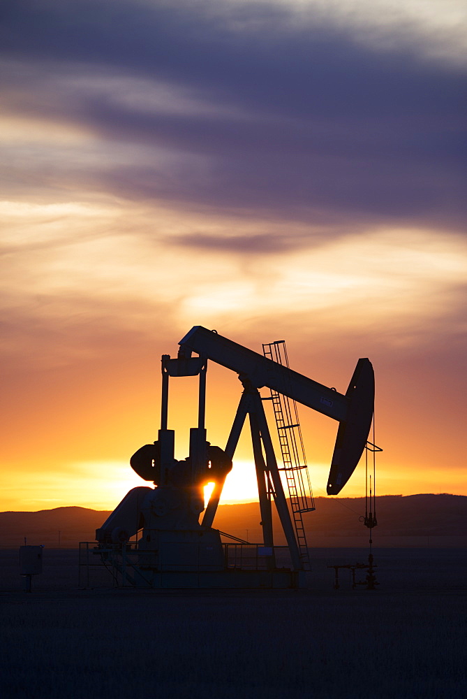 A pumpjack at an oil drilling site at sunset, Oilfield pumpjack, Canada