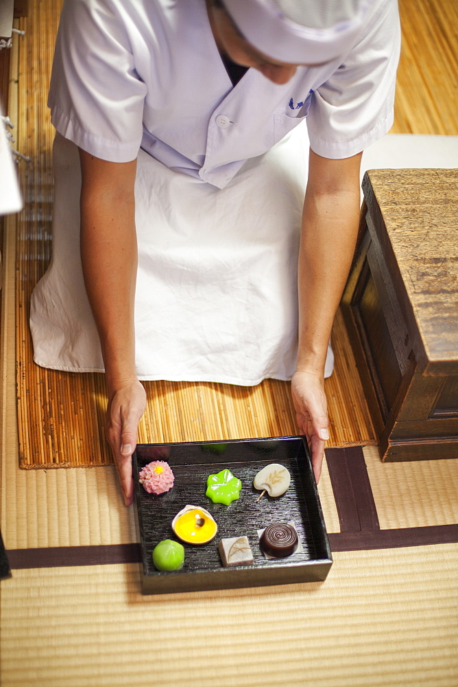 A small artisan producer of specialist treats, sweets called wagashi. A chef presenting a tray of selected wagashi of different shapes and flavours, Japan