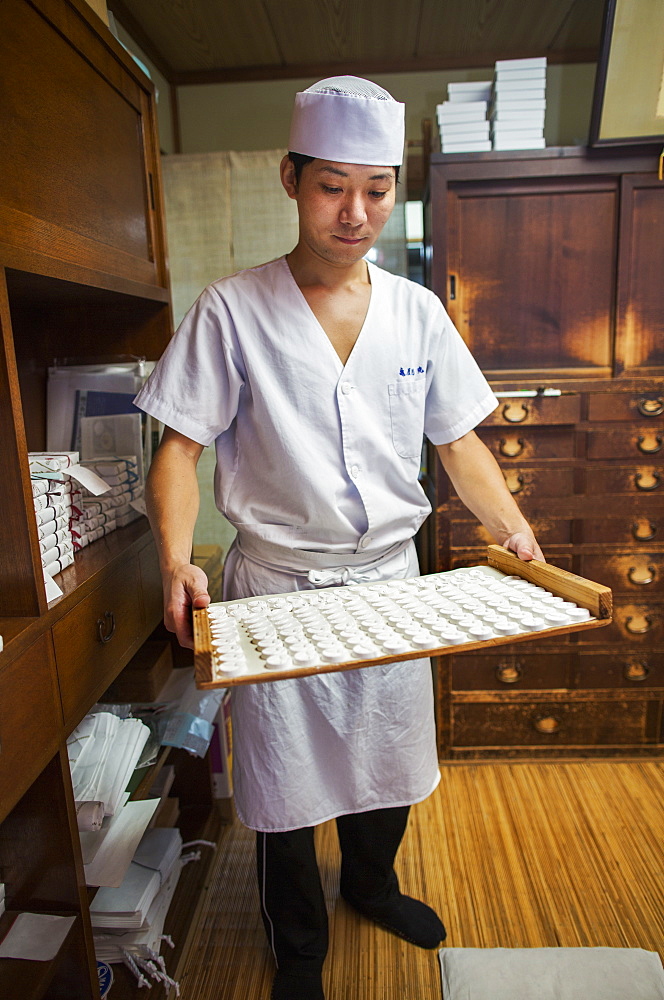 A small artisan producer of specialist treats, sweets called wagashi/ A man holding a tray of sweets, Japan