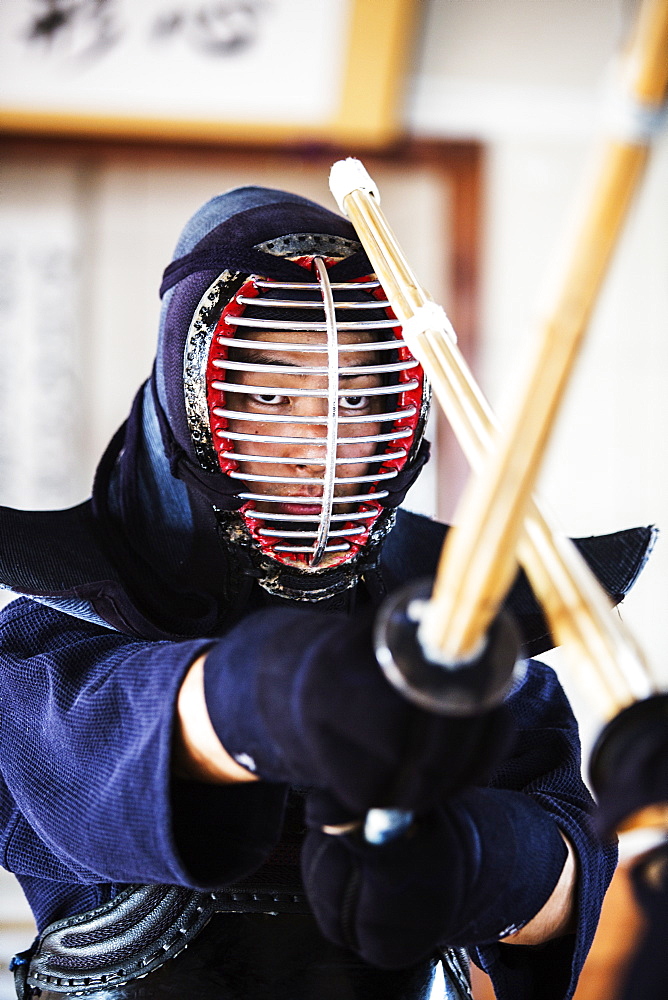 Close up of Japanese Kendo fighter wearing Kendo mask in combat pose, Kyushu, Japan