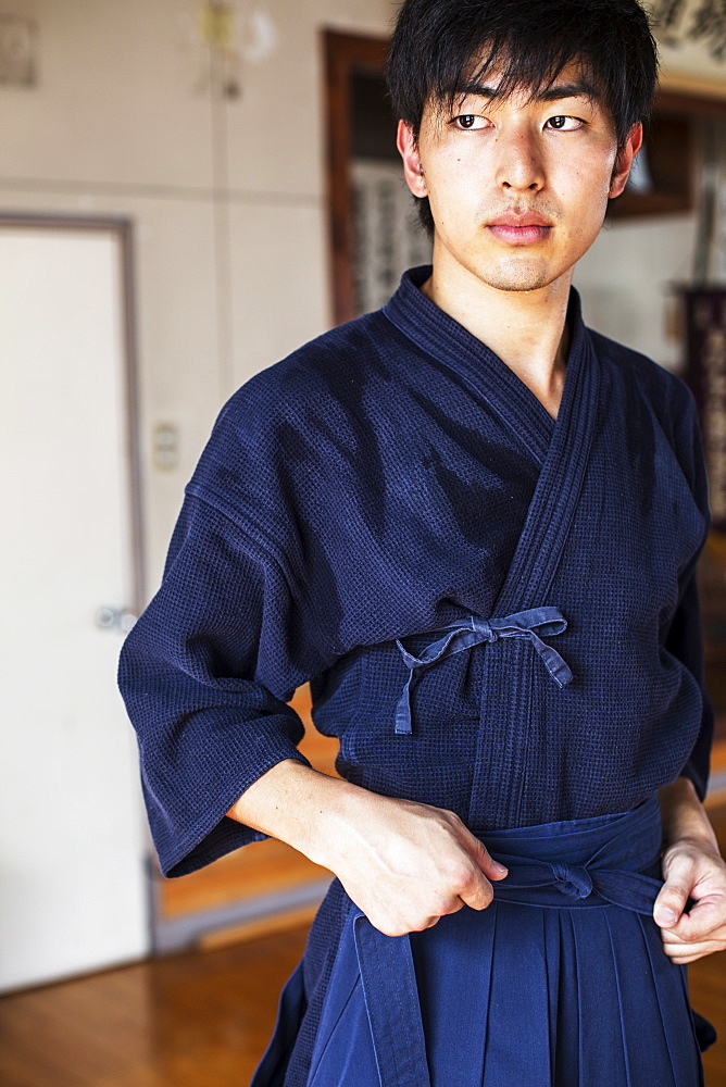 Male Japanese Kendo fighter tying belt of his blue Kendo uniform, Kyushu, Japan