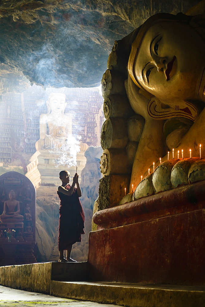 Asian monk lighting incense in temple