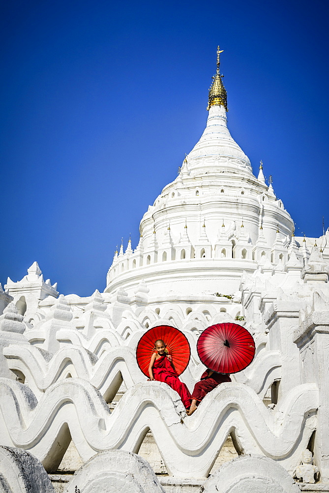 Asian monks sitting under umbrellas at historic temple, Mingun, Mandala, Myanmar