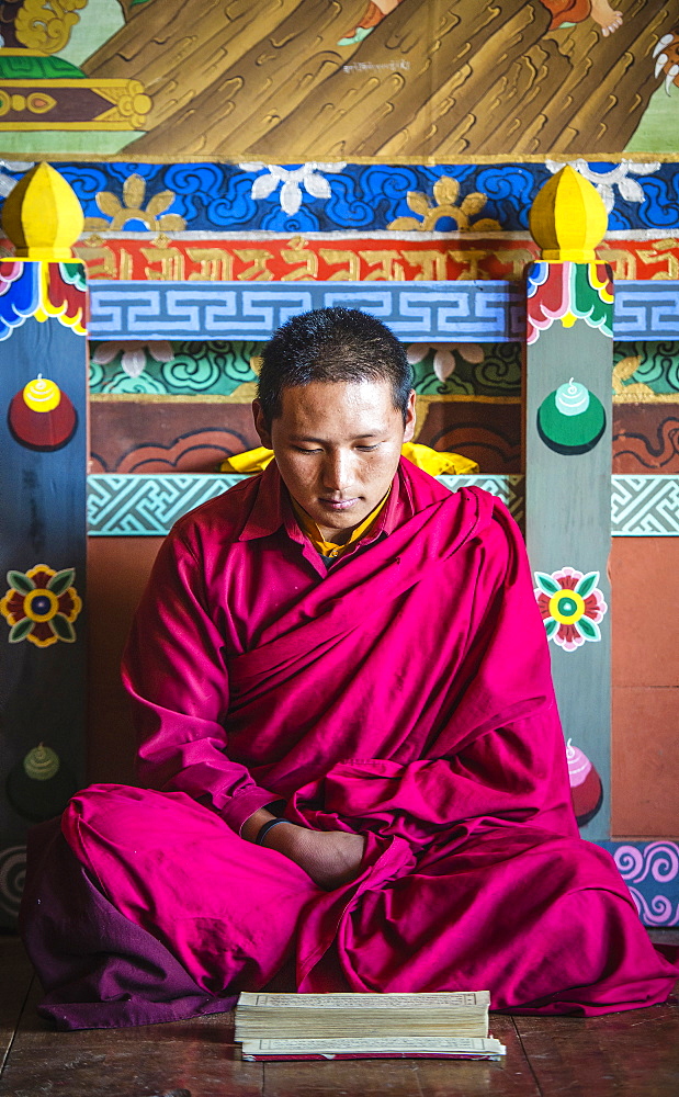 Asian monk reading on temple floor, Bhutan, Kingdom of Bhutan