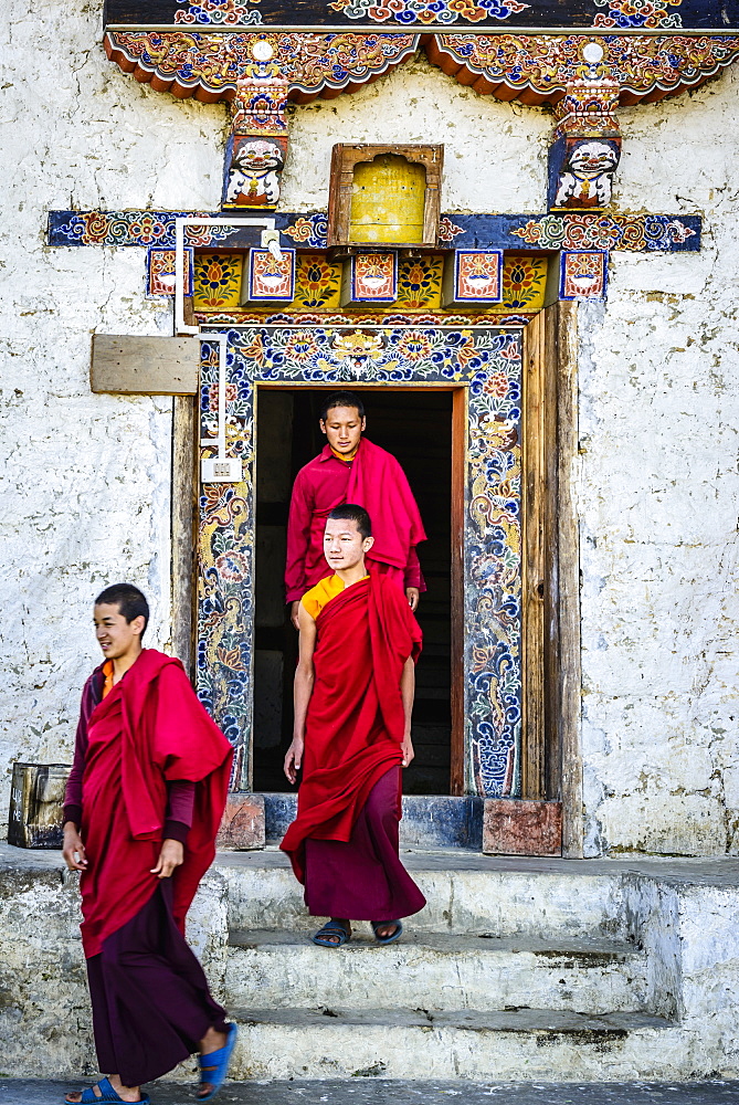 Asian monks walking out temple doorway, Bhutan, Kingdom of Bhutan