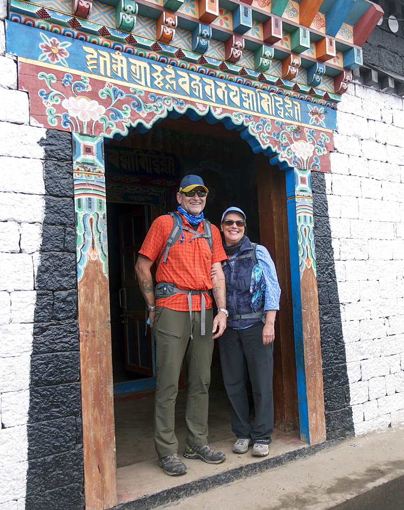 Caucasian couple standing in ornate doorway, Lukla, Khumbu region, Nepal