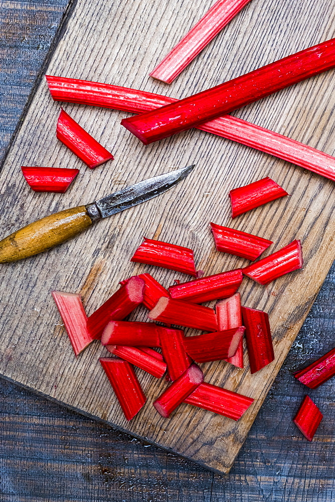 High angle close up of slices of rhubarb and knife on wooden cutting board, Oxfordshire, England