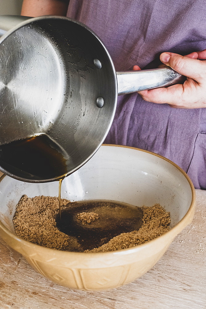 High angle close up of person pouring liquid into mixing bowl with baking ingredients, England