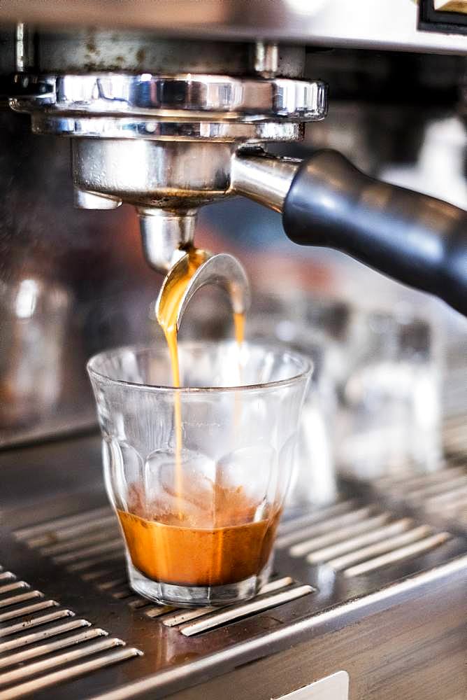 A commercial expresso machine in a coffee shop making an expresso shot