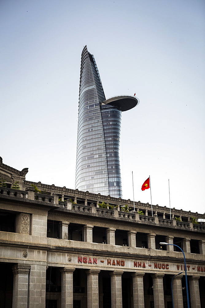 Facade of historic stone building with contemporary skyscraper in the background, Vietnam