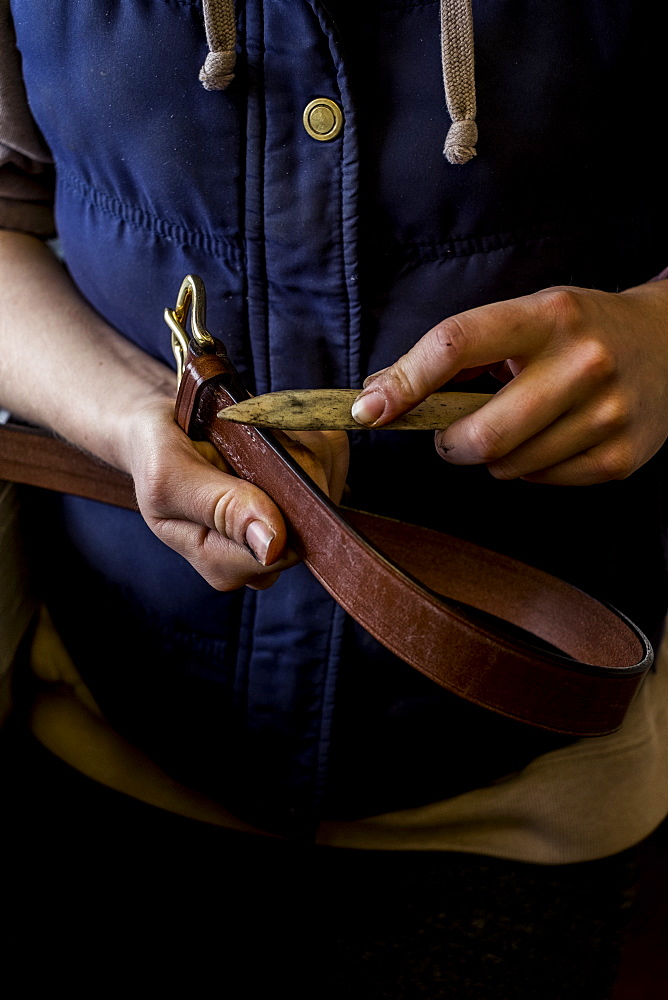 Close up of person in saddler's workshop holding leather strap, Berkshire, United Kingdom