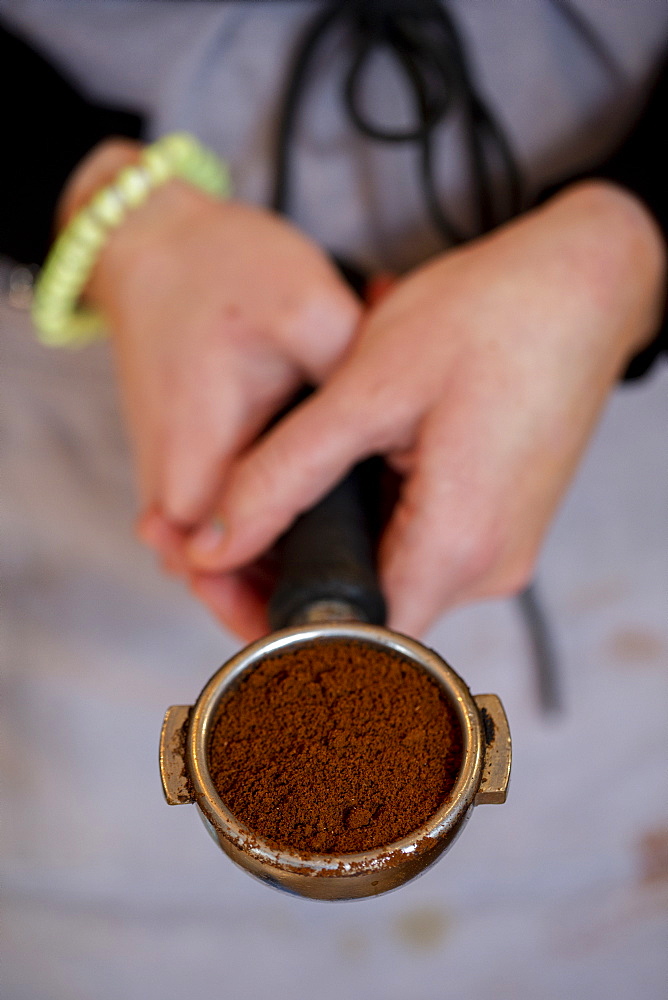 High angle close up of barista holding espresso machine portafilter