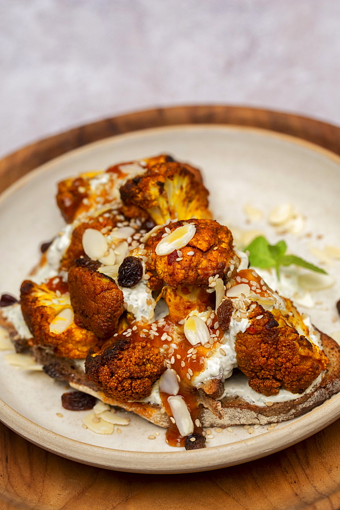 High angle close up of roasted cauliflower on toasted sourdough bread on a plate