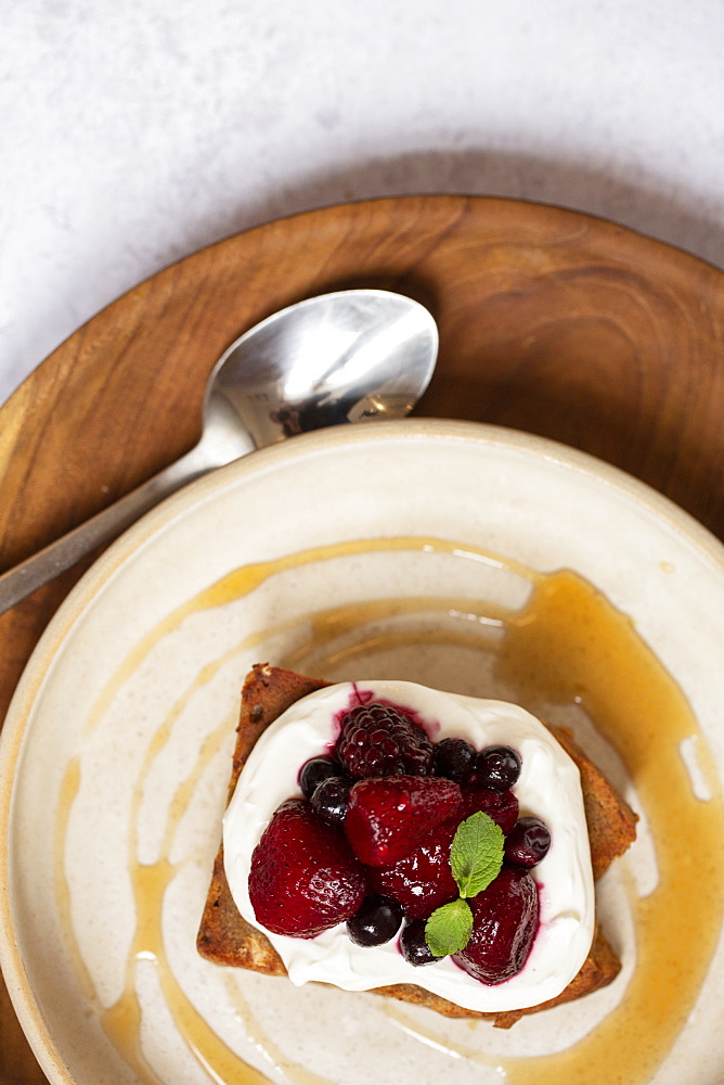 High angle close up of banana bread topped with yoghurt and mixed berries in a cafe