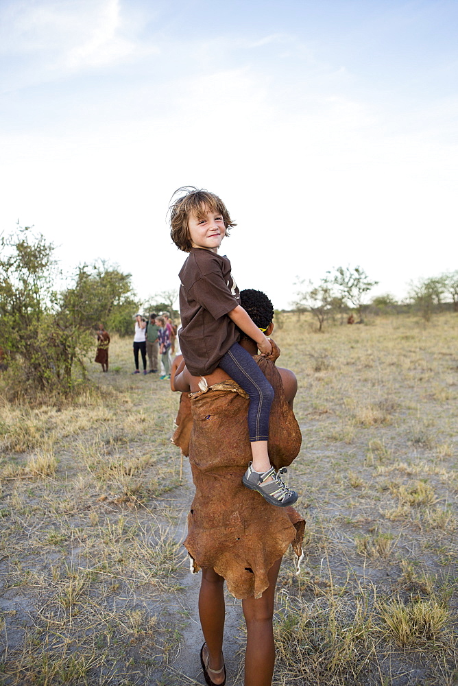 Five year old boy riding on shoulders of a San bushman