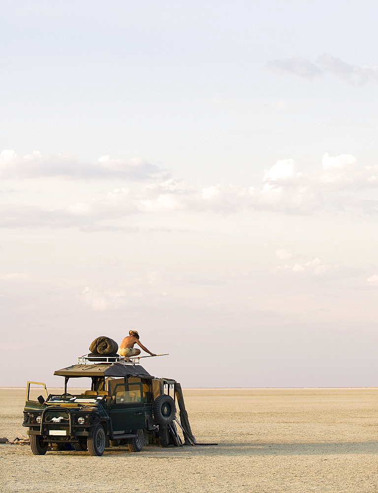 Man standing on top of 4x4 parked on the Makadikadi Salt Pans in Botswana