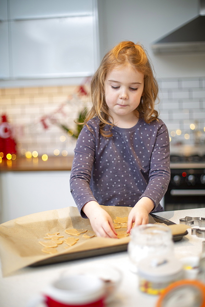 Girl standing in kitchen, baking Christmas cookies