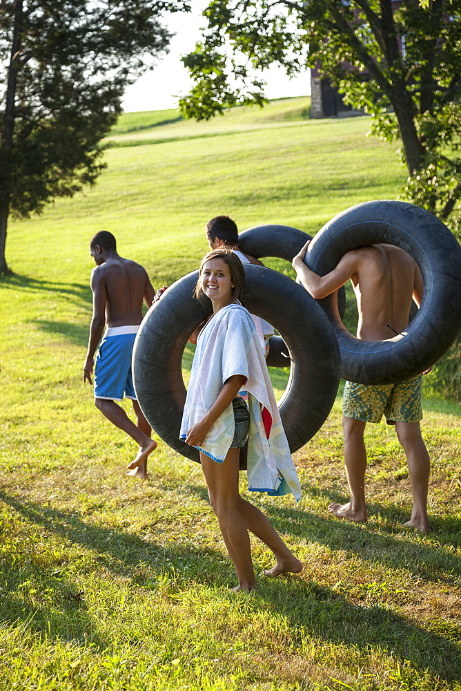 A group of young people, boys and girls, holding towels and swim floats, going for a swim, Maryland, USA