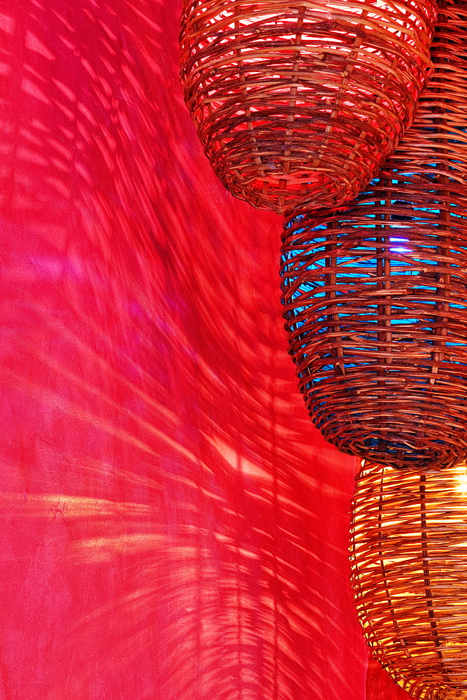 Wicker light fixtures casting shadows on red wall