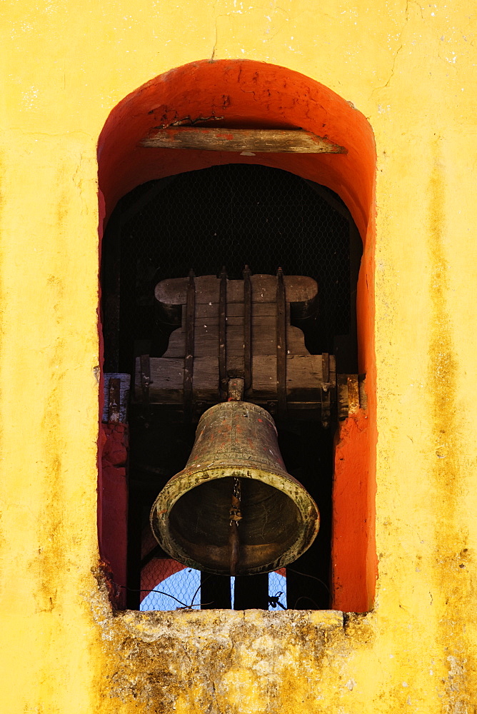 Bell tolling in a yellow painted arch