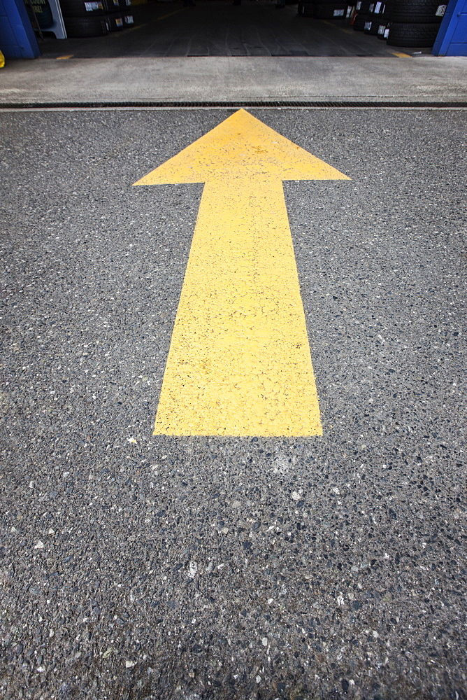 Arrow painted on the road leads to the open garage door of an auto repair shop