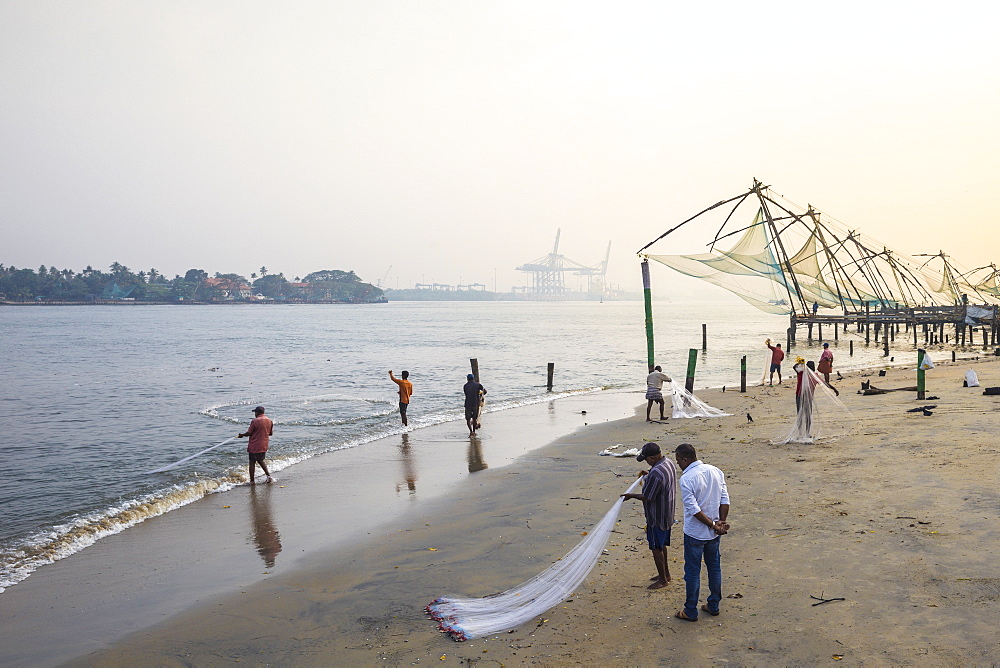 Fishermen on beach in front of Chinese fishing nets, Fort Kochi, Cochin (Kochi), Kerala, India, Asia