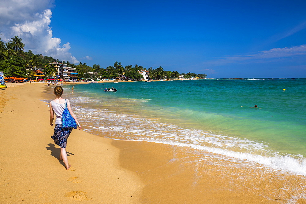 Tourist walking along Unawatuna Beach, a beautiful sandy beach on the South Coast of Sri Lanka, Asia