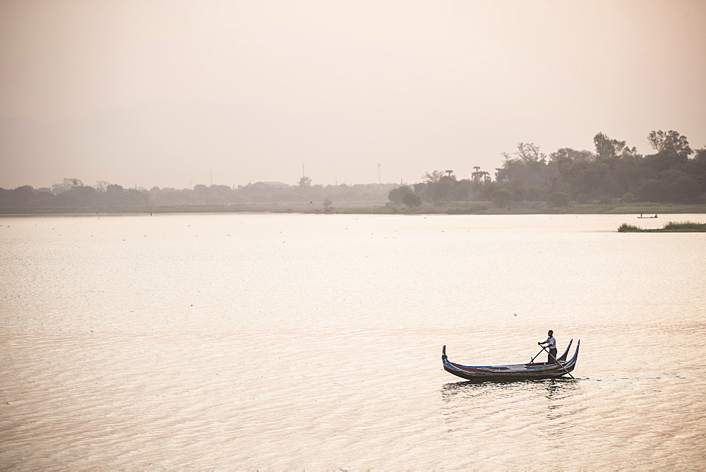 Rowing boat on Taungthaman Lake at sunrise, at U Bein Bridge, Mandalay, Mandalay Region, Myanmar (Burma), Asia