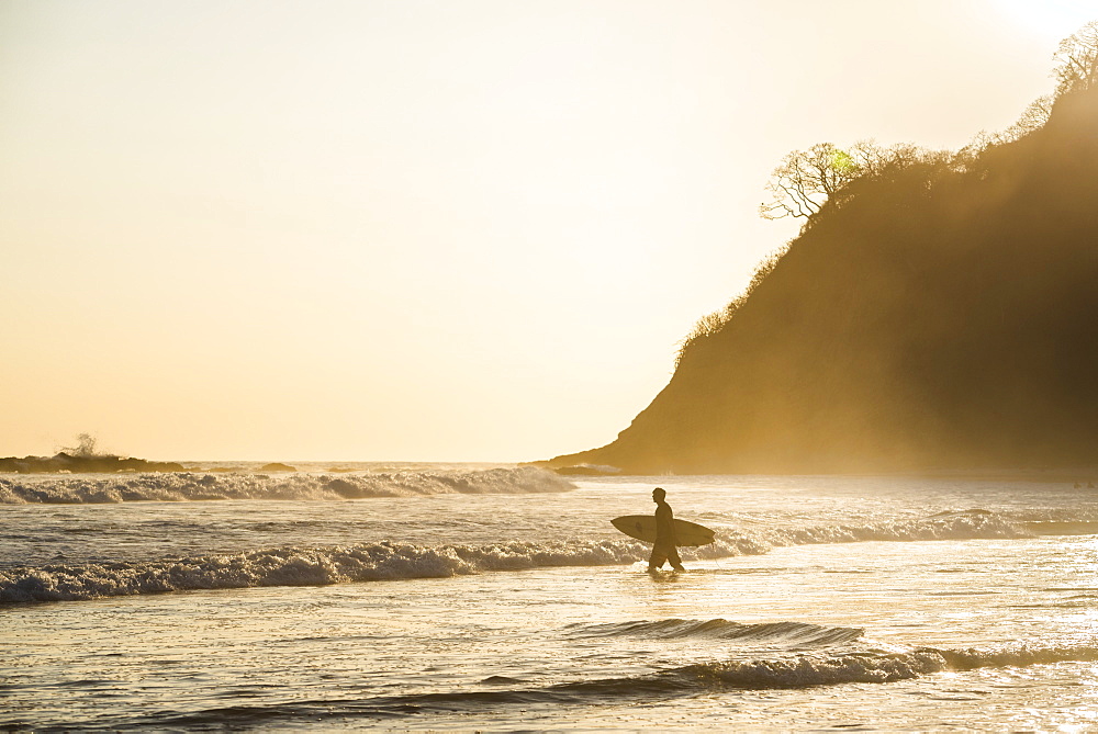 Surfers surfing on a beach at sunset, Nosara, Guanacaste Province, Pacific Coast, Costa Rica, Central America