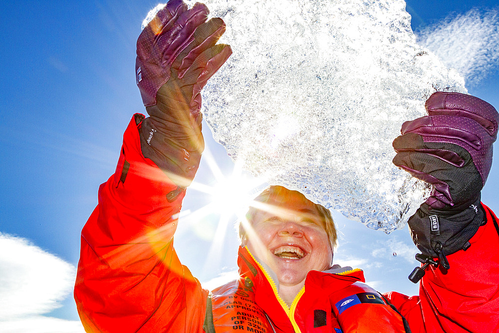 Guest from the Lindblad Expedition ship National Geographic Explorer holding up a block of ice in the Svalbard Archipelago, Norway, Arctic, Europe