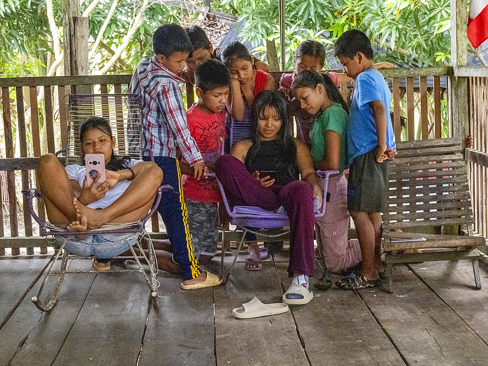 Young kids gathered around a phone watching television in the village of Amazonas, Peru.