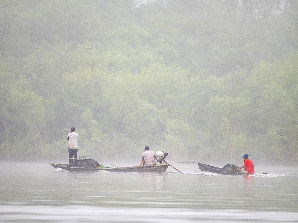 Local people in a traditional dugout wooden boat deep within the Pacaya Samiria Preserve, Peru.