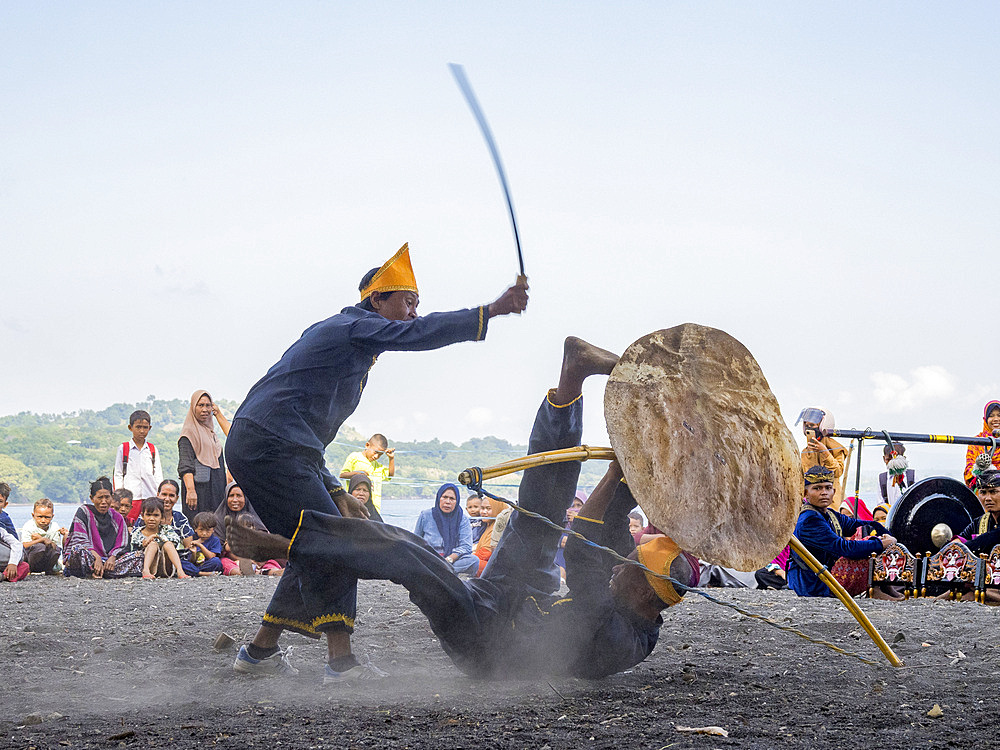 Ceremonial mock fighters perform a ritualized battle with whip, shield, and bow on Sumbawa Island, Indonesia.