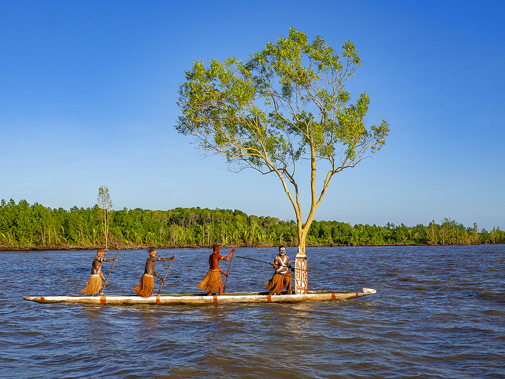 Male paddlers from the village of Per perform in a ritualistic greeting ceremony, Asmat Region, Papua, Indonesia.