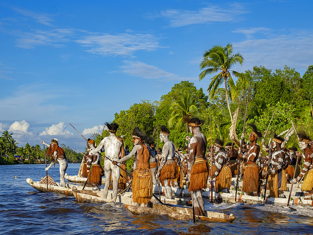 Male paddlers from the village of Per perform in a ritualistic greeting ceremony, Asmat Region, Papua, Indonesia.