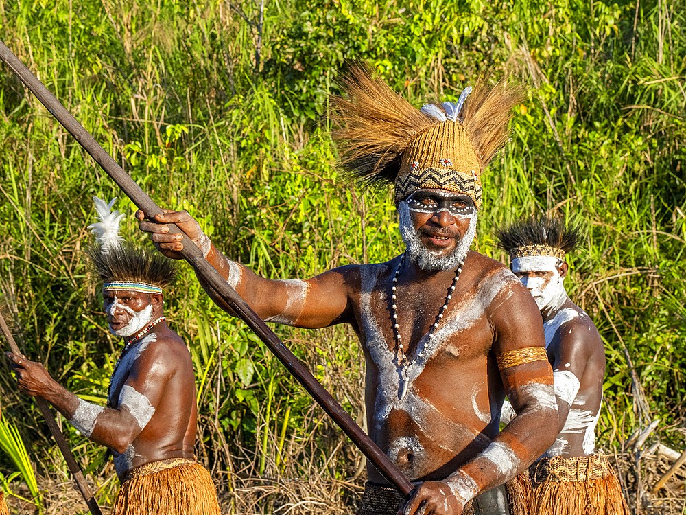 Male paddlers from the village of Per perform in a ritualistic greeting ceremony, Asmat Region, Papua, Indonesia.