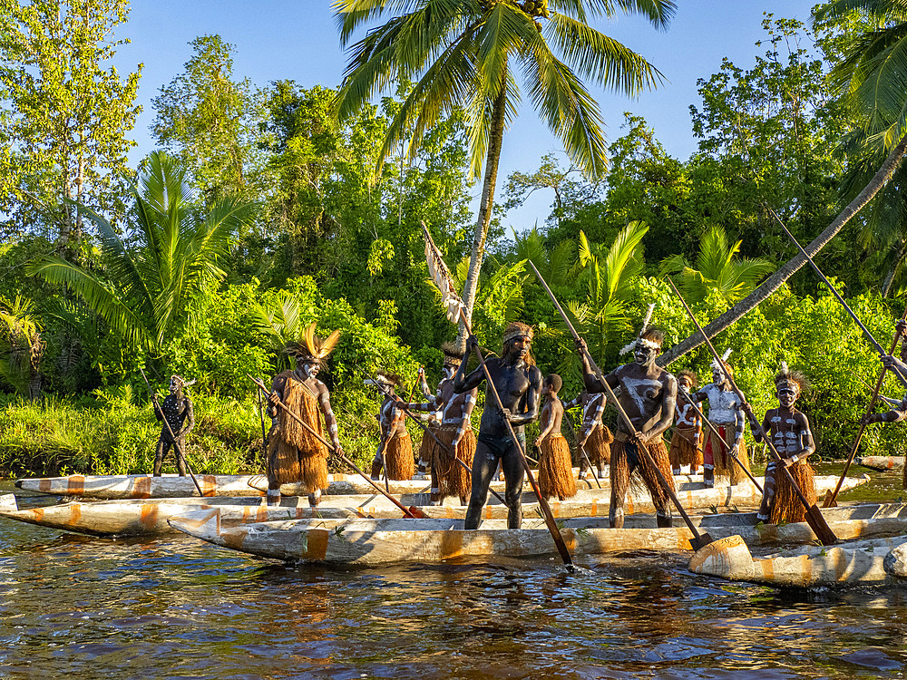 Male paddlers from the village of Per perform in a ritualistic greeting ceremony, Asmat Region, Papua, Indonesia.