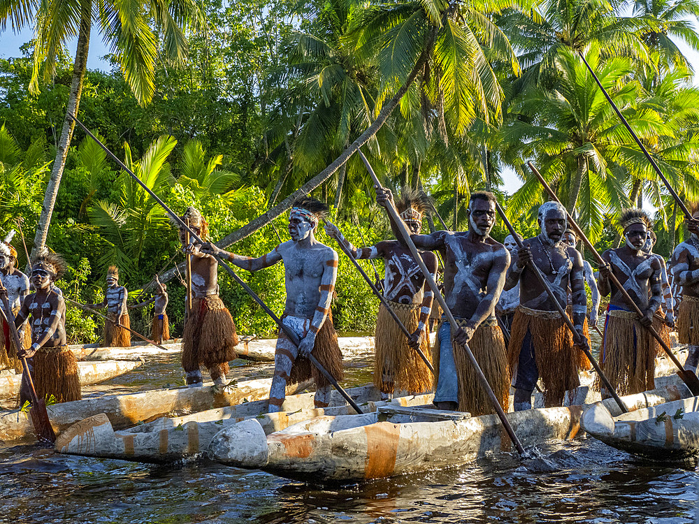 Male paddlers from the village of Per perform in a ritualistic greeting ceremony, Asmat Region, Papua, Indonesia.