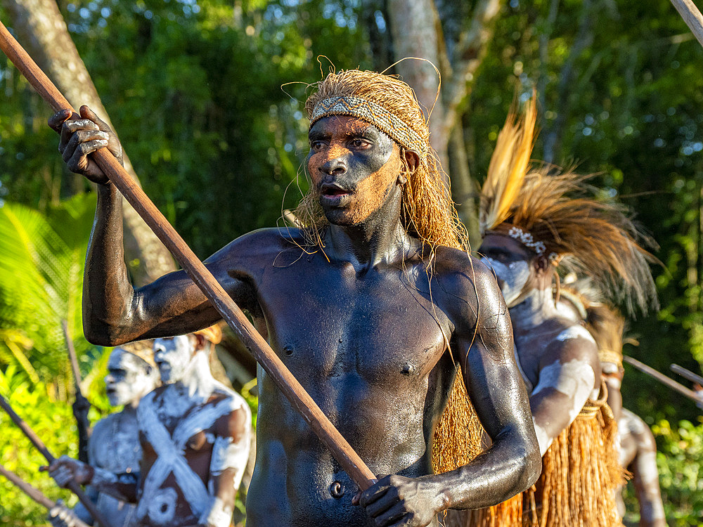 Male paddlers from the village of Per perform in a ritualistic greeting ceremony, Asmat Region, Papua, Indonesia.