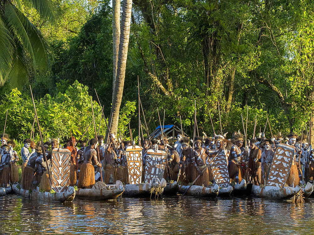 Male paddlers from the village of Per perform in a ritualistic greeting ceremony, Asmat Region, Papua, Indonesia.